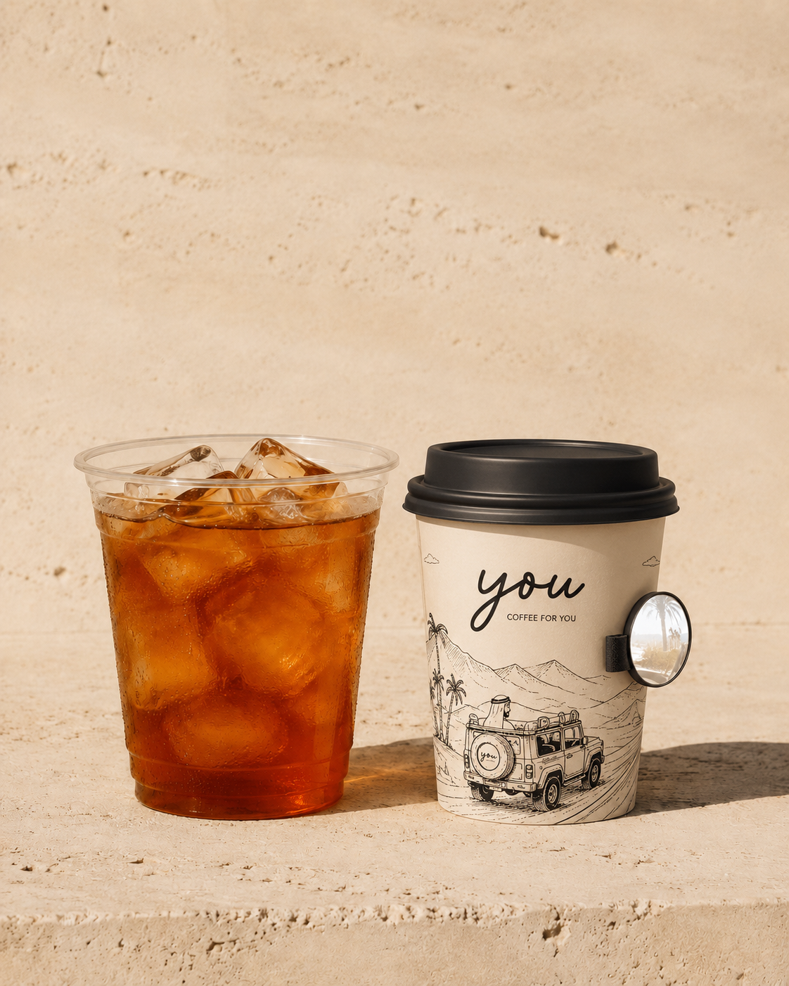 Iced pour-over coffee beside an illustrated YOU. takeaway cup with an attached round mirror